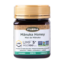 A jar of Flora Manuka Honey with labels indicating UMF 5+ and MGO 100+. The jar is set against a white background.
